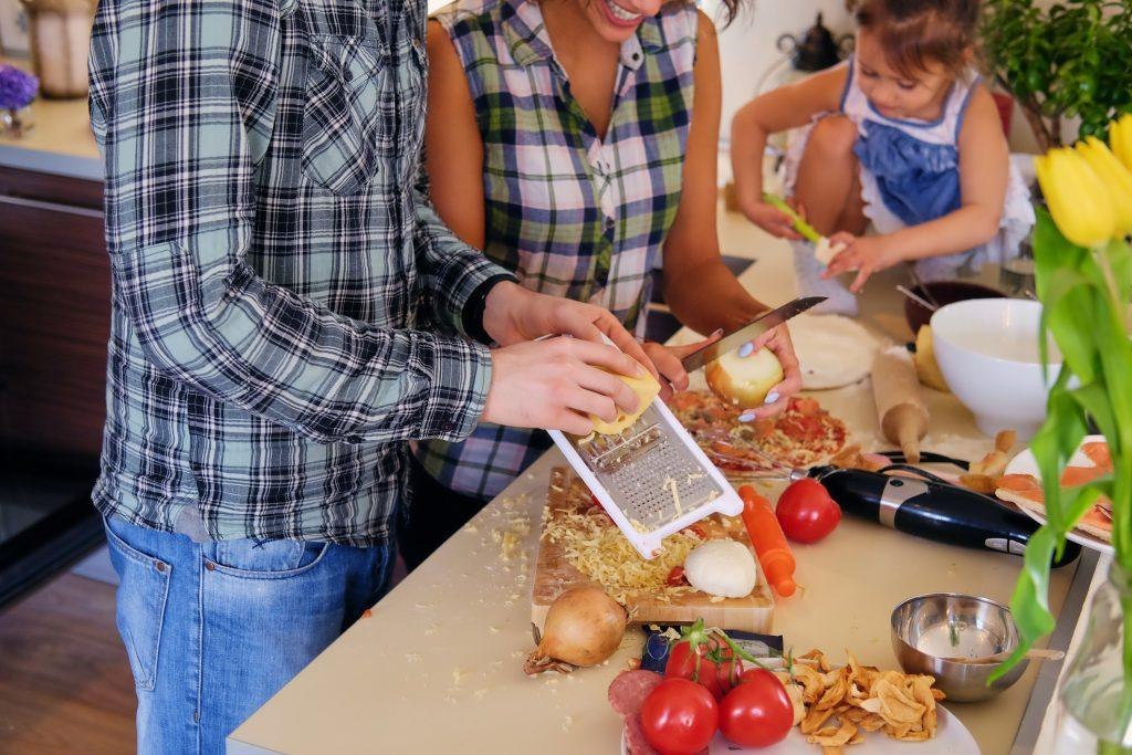 A person and person cutting vegetables in a kitchen  Description automatically generated